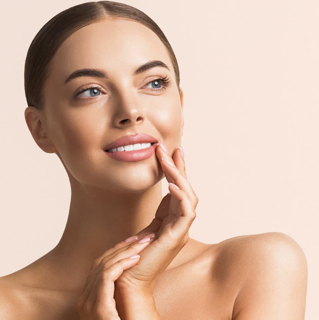 Woman touching her cheek and jawline, showing firm, healthy skin against a warm cream background